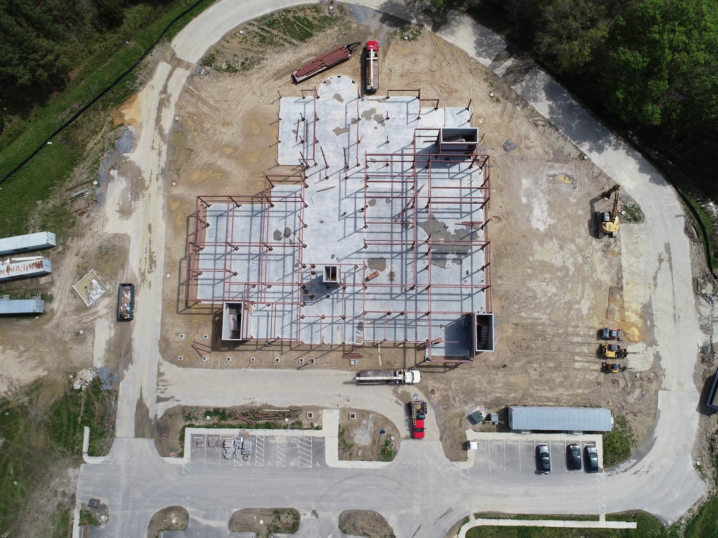 Aerial view of a commercial building under construction showing a completed concrete slab foundation with structural steel framing rising from column bases