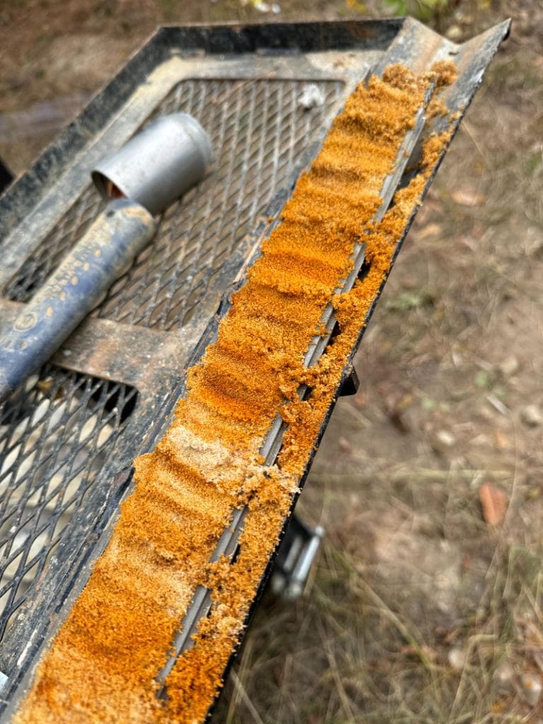Close-up of a hollow stem auger bit with a rust-colored soil core sample collected during subsurface geotechnical investigation