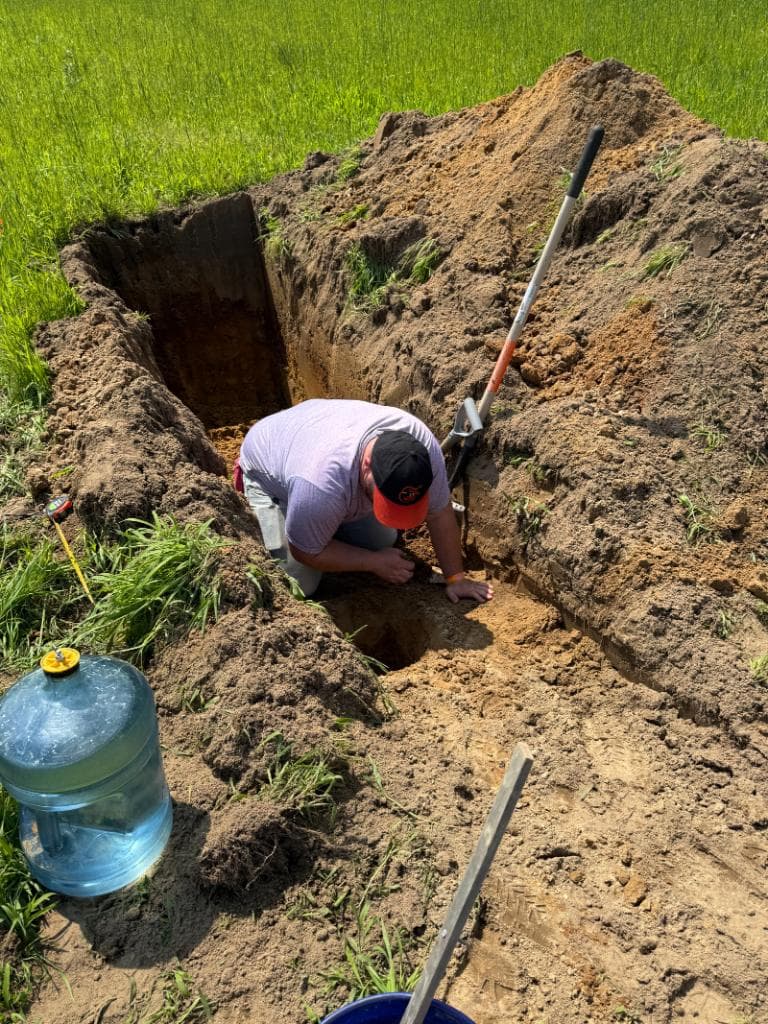 Environmental technician conducting soil evaluation in an excavated test pit