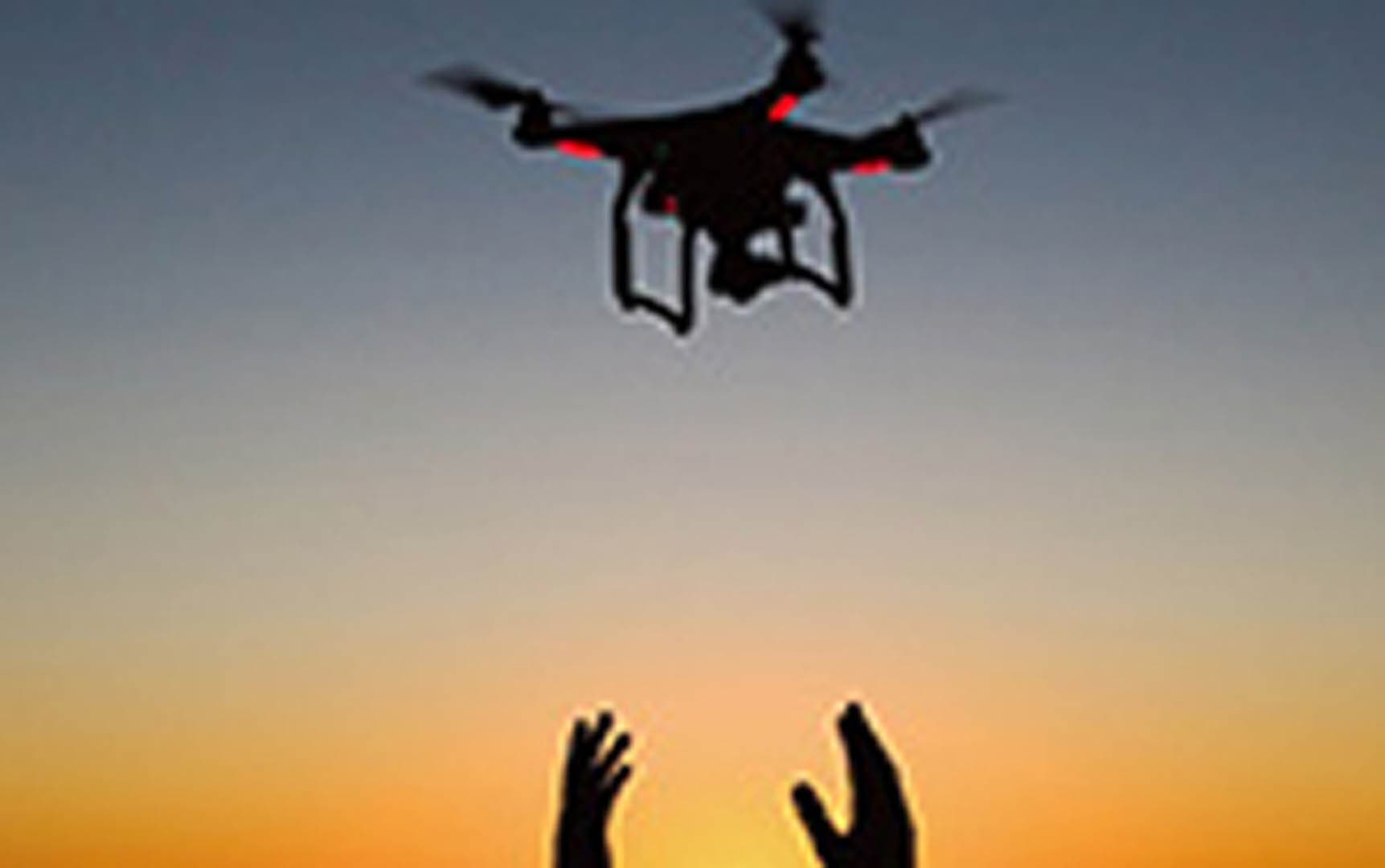 Silhouette of a quadcopter drone being launched by an operator against a vivid orange and blue sunset sky